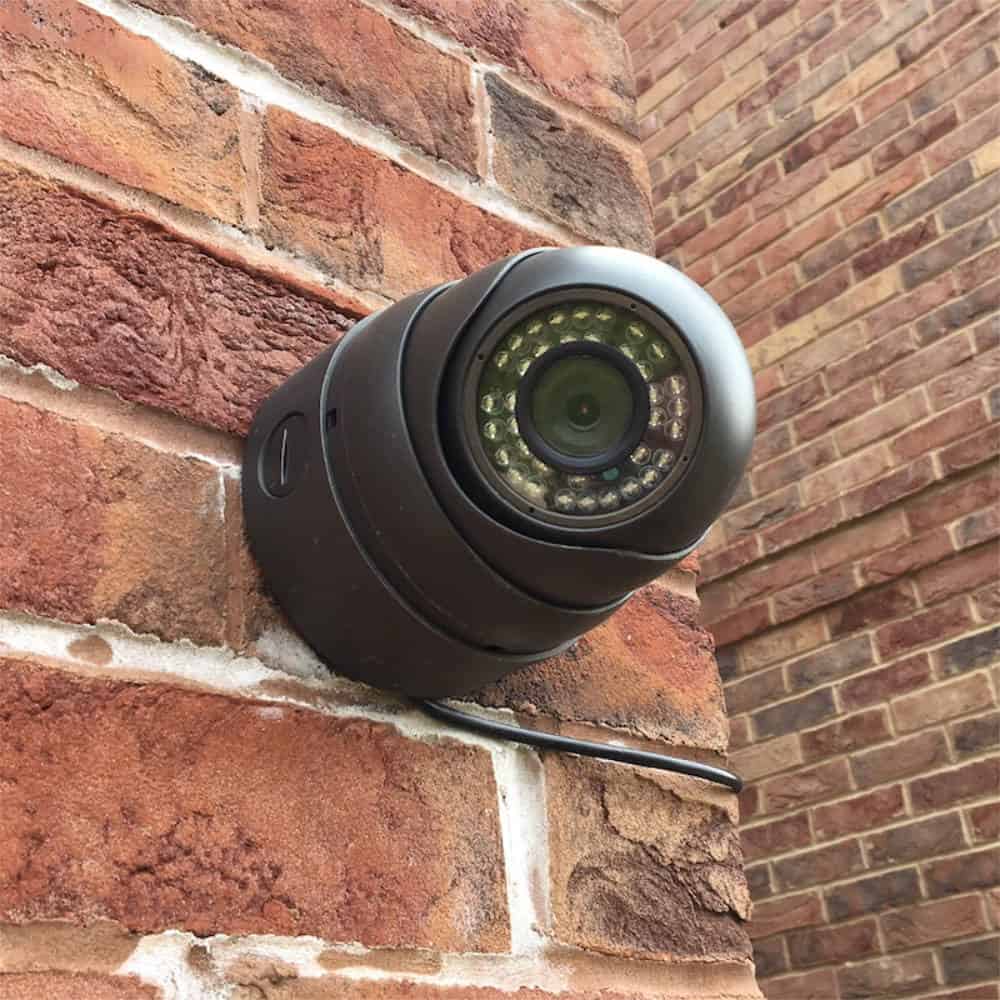 A CCTV security camera mounted on a brick wall.