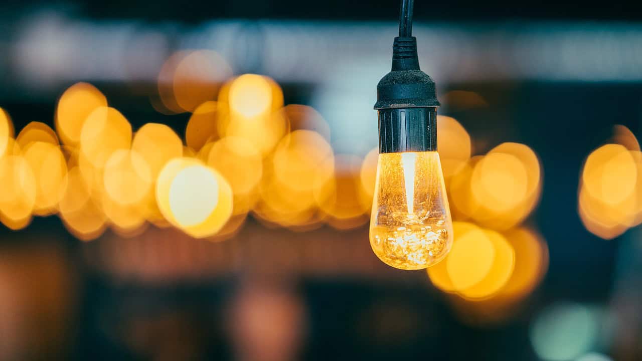 Close-up of a glowing light bulb against a blurred background of similar lights.